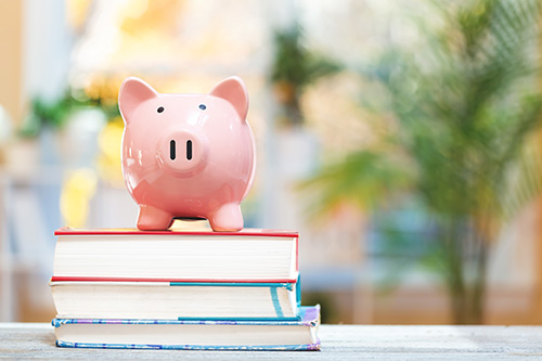 Alcancía en forma de cerdito encima de tres libros